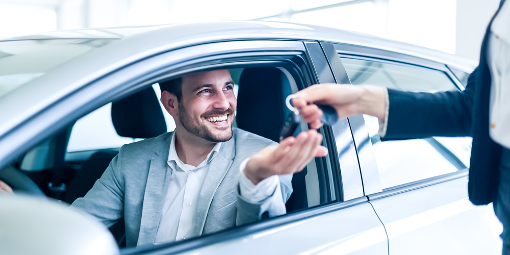 Person giving keys to man in a car